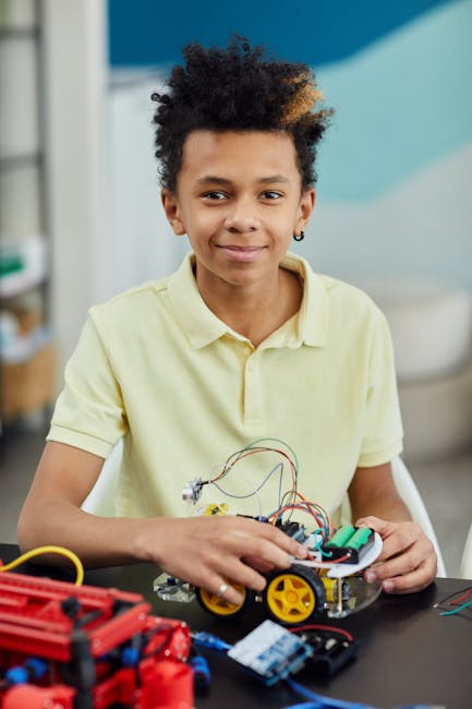 Smiling kid holding a robot he's building at a STEM workshop